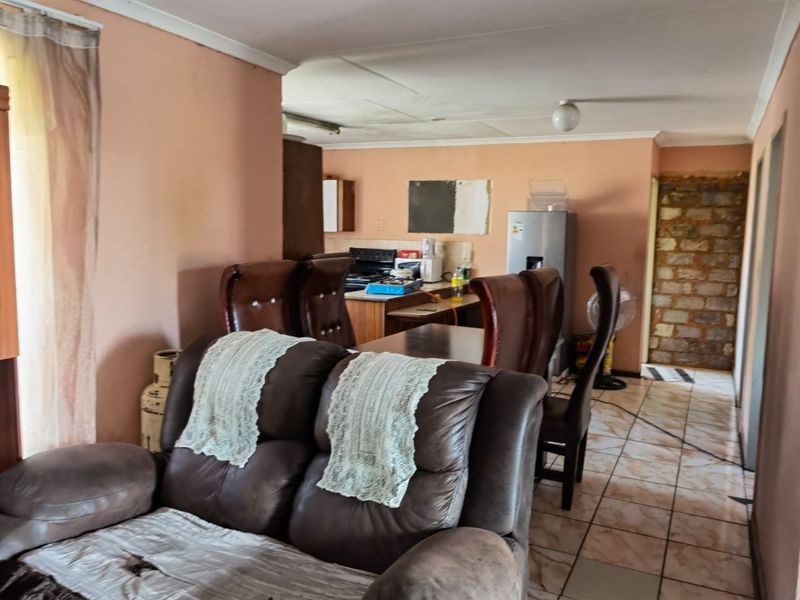 Open plan living and kitchen area featuring tiled flooring and a rustic stone feature wall, offering a functional layout for daily living.