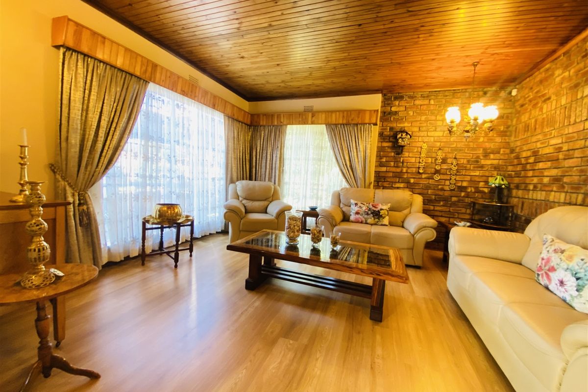 A living room featuring a warm timber tongue and groove ceiling, exposed brick feature wall, and light-toned laminate flooring.