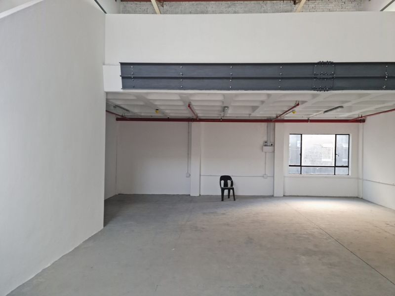 Spacious industrial open-plan area featuring exposed steel beams, concrete waffle ceiling, and fire sprinkler system, offering a versatile blank canvas for commercial use.