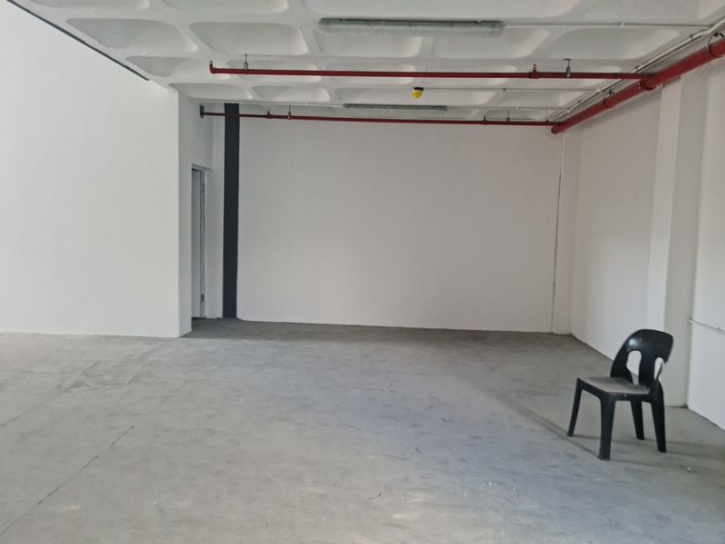 An open-plan industrial utility space featuring an exposed waffle slab ceiling, fire sprinkler system, and durable concrete flooring.