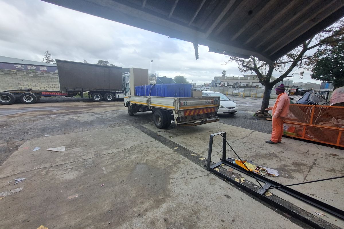 Industrial yard area featuring a concrete loading bay, covered outdoor space, and direct access to the street and parking area.