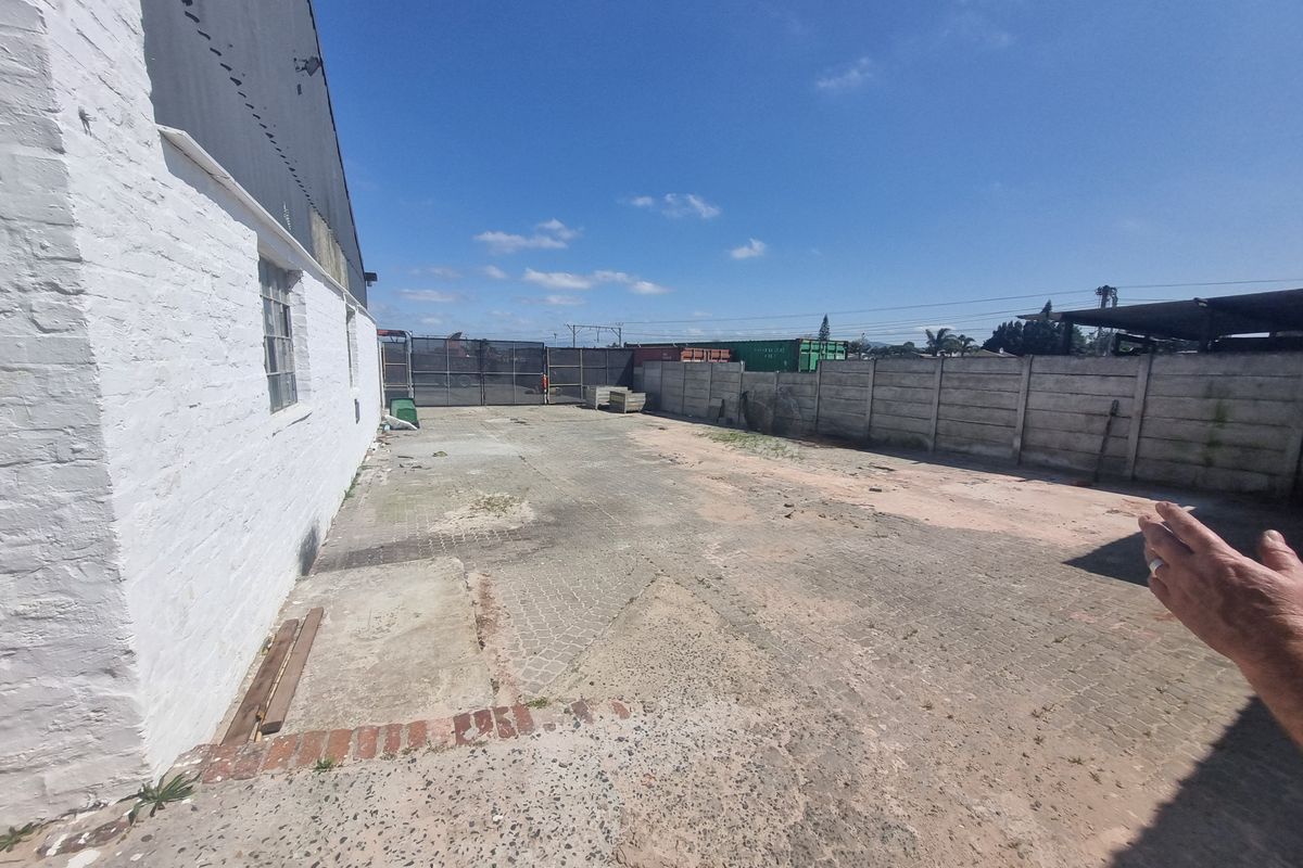 An expansive industrial exterior yard area featuring concrete paving, perimeter boundary walls, and direct access to the main building structure.