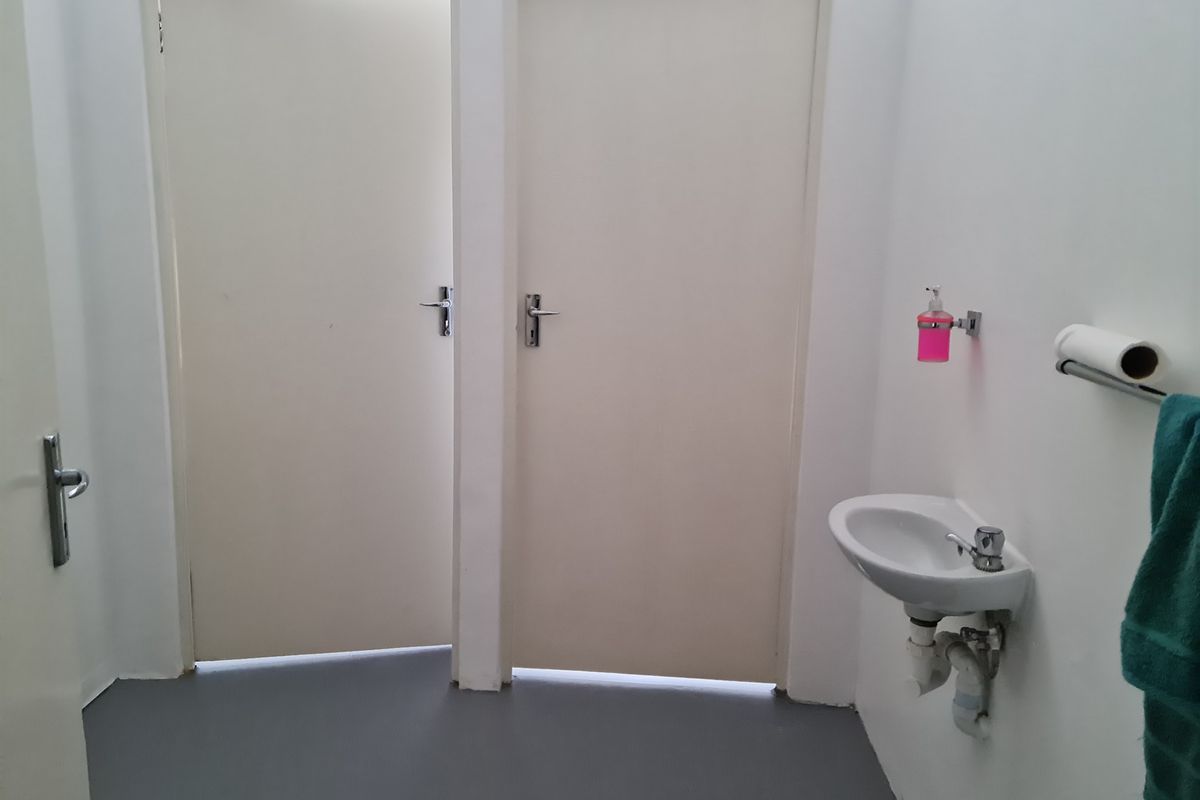 A functional industrial restroom area featuring a wall-mounted basin and two access doors.
