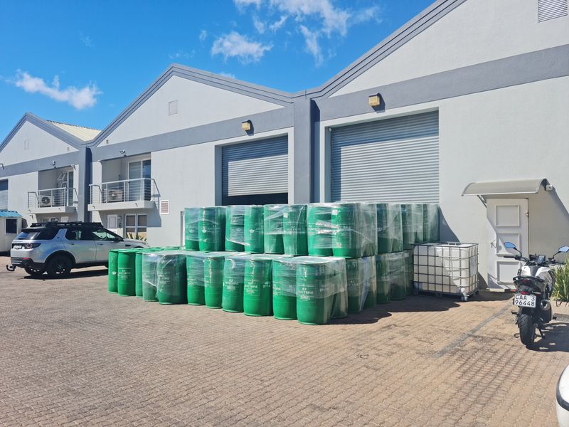 Industrial warehouse exterior featuring paved frontage, roller shutter doors, and modern facade finishes with balcony access.