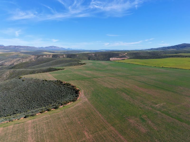 An expansive aerial view of the farm property, showcasing large tracts of cultivated agricultural land and surrounding natural landscape.