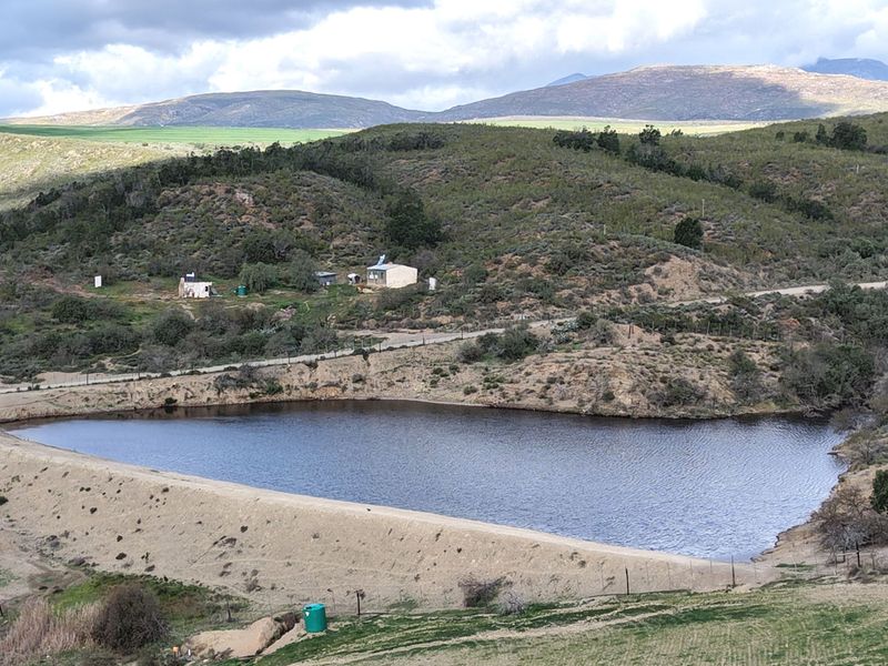 A scenic elevated view of a farm dam with surrounding rolling hills and rural landscape.