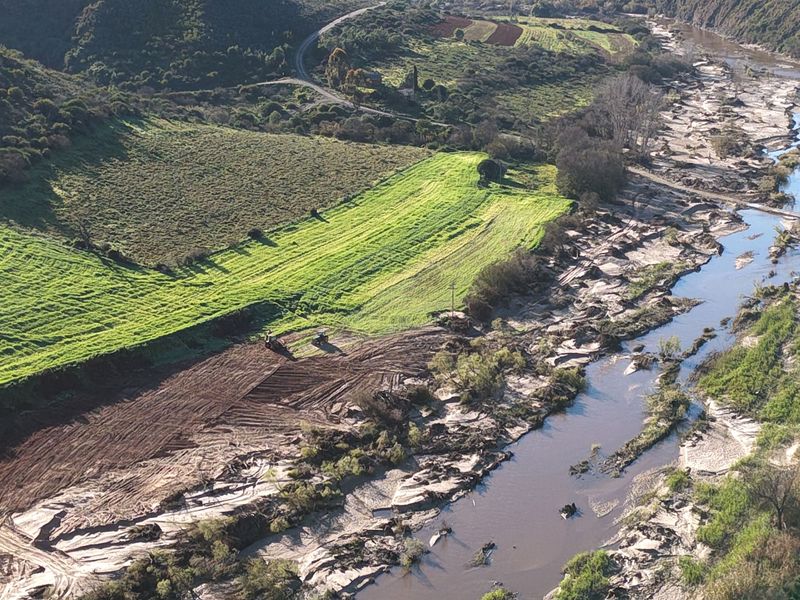 An aerial view of the small holding property featuring expansive agricultural land and pasture bordering a natural river system.