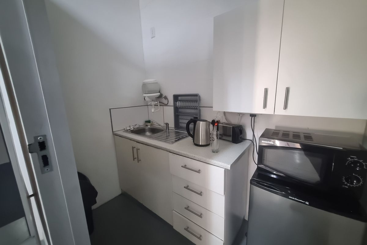 Compact kitchenette area featuring built-in cabinetry, a stainless steel sink, and laminate countertops, suitable for a small office or utility space.