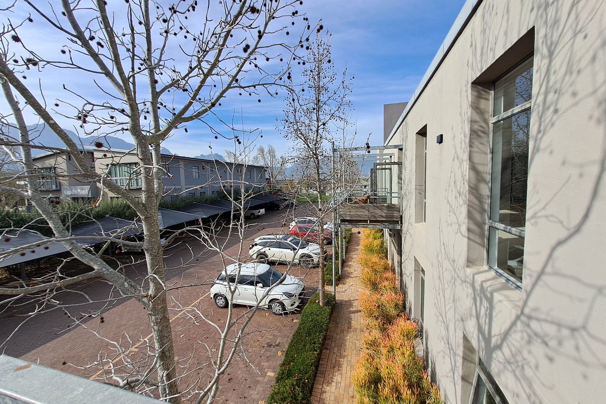 Elevated view overlooking the office complex parking area, featuring paved driveways, covered parking bays, and landscaped garden borders.