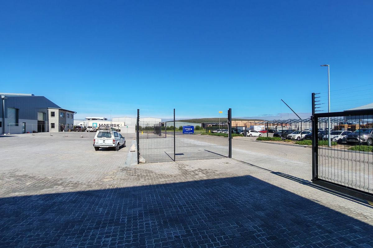 Spacious industrial yard featuring paved surfaces, secure perimeter fencing with electric wire, and gated access points within a well-maintained commercial complex.