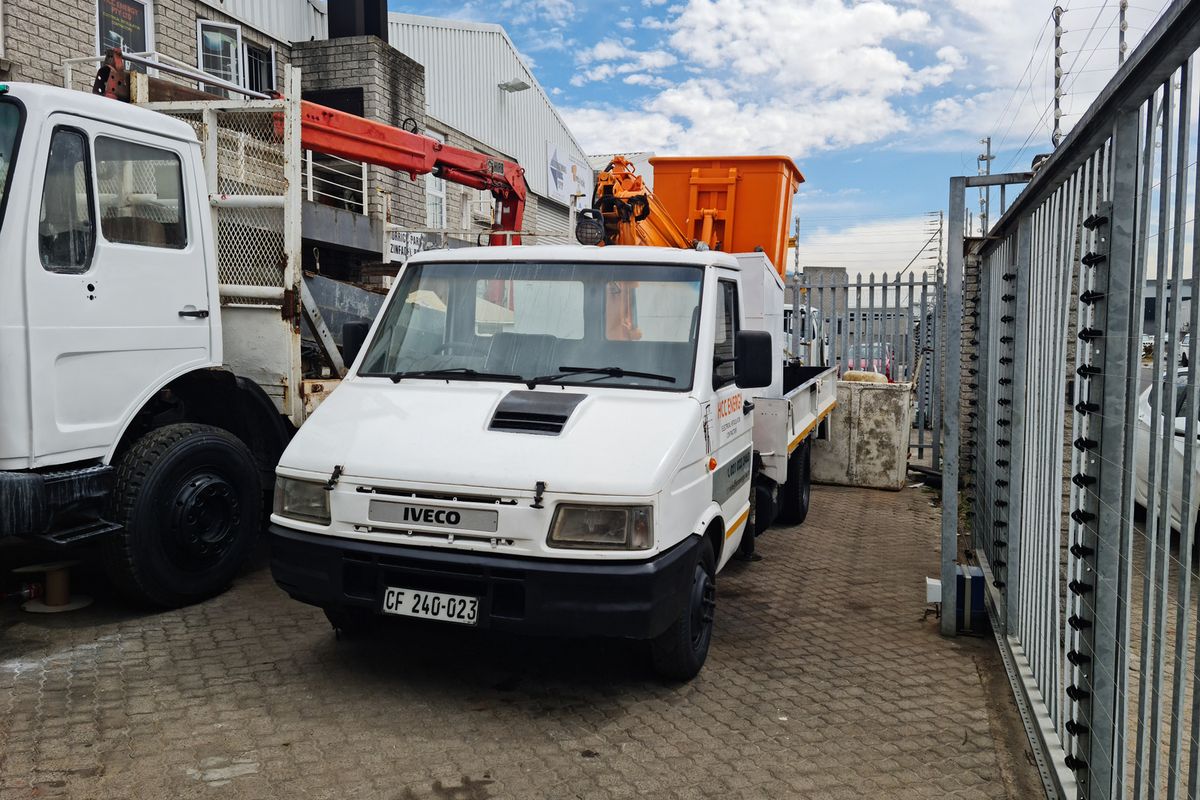 Exterior view of an industrial property yard featuring paved ground, perimeter security fencing, and industrial utility vehicles parked on site.
