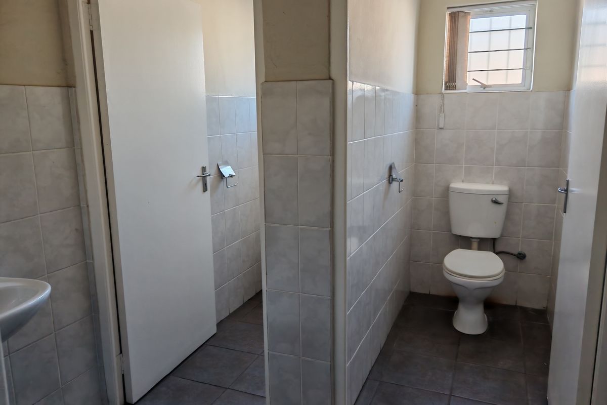 Functional industrial restroom facility featuring tiled walls, ceramic toilet suite, and separate cubicle access.