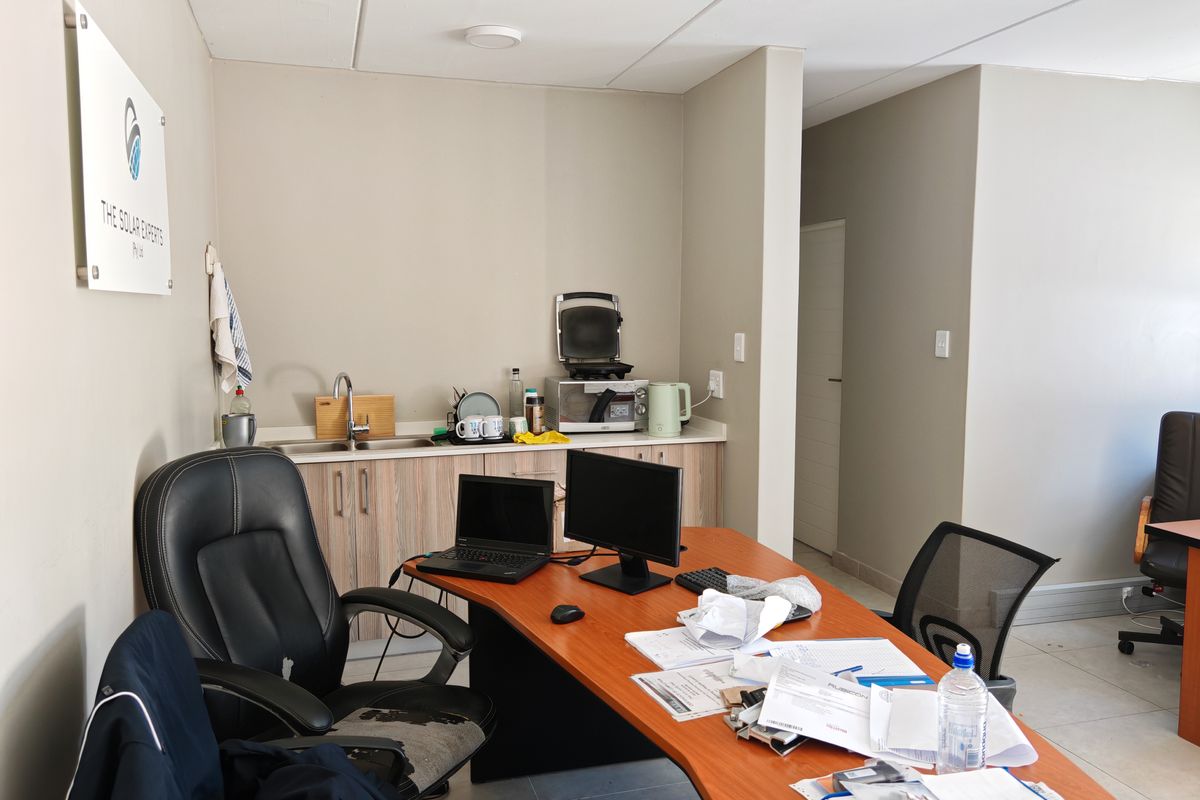 A functional office kitchenette area featuring built-in cabinetry, a stainless steel sink, and tiled flooring, integrated into a professional workspace.
