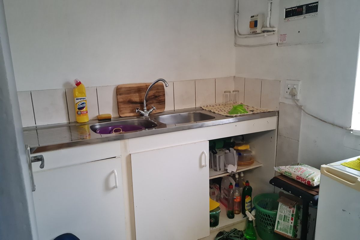 A functional kitchenette area featuring a stainless steel sink, built-in base cabinetry, and an electrical distribution board.