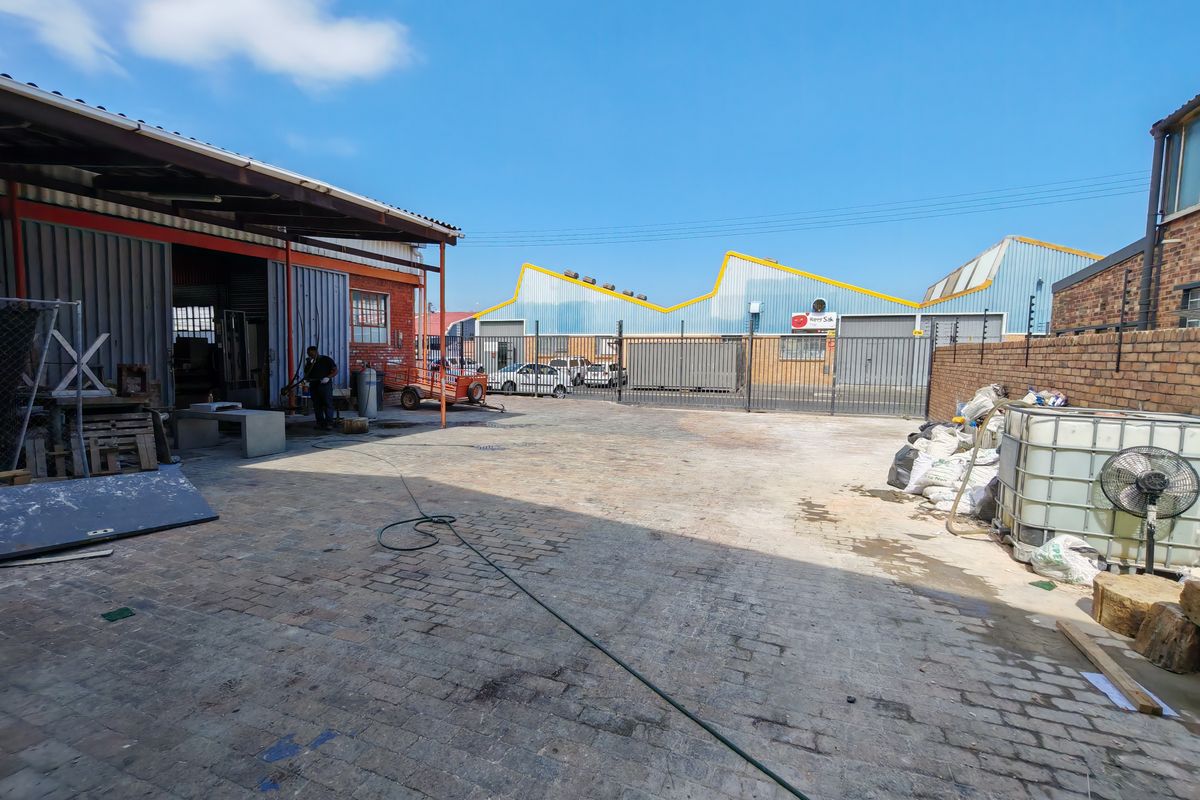 Spacious industrial yard area featuring paved flooring, perimeter brick walling, and secure metal fencing, suitable for logistics or storage operations.