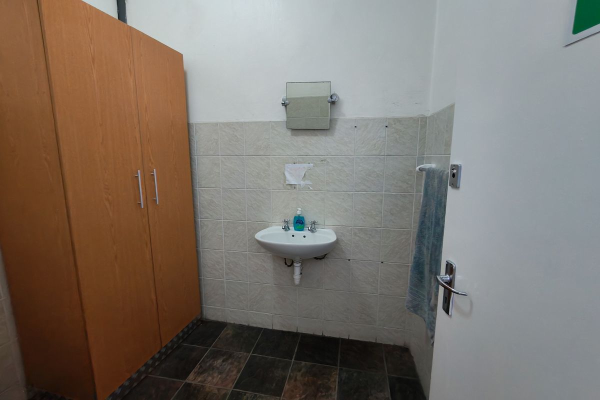 A functional washroom area featuring a wall-mounted basin, tiled splashback, and built-in storage cabinetry.