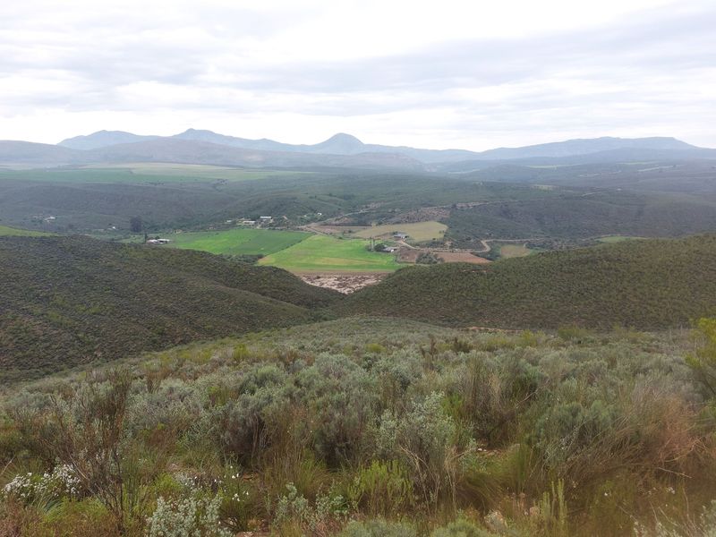 A panoramic landscape view overlooking the expansive farm valley, rolling hills, and distant mountain ranges.