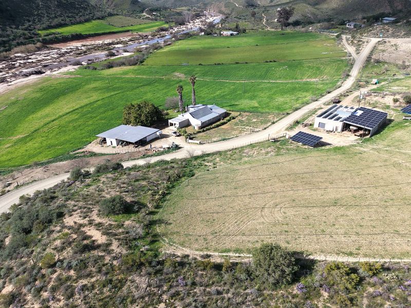 Aerial view of a rural farm property featuring multiple outbuildings, solar panel installations, and extensive agricultural land with river access.