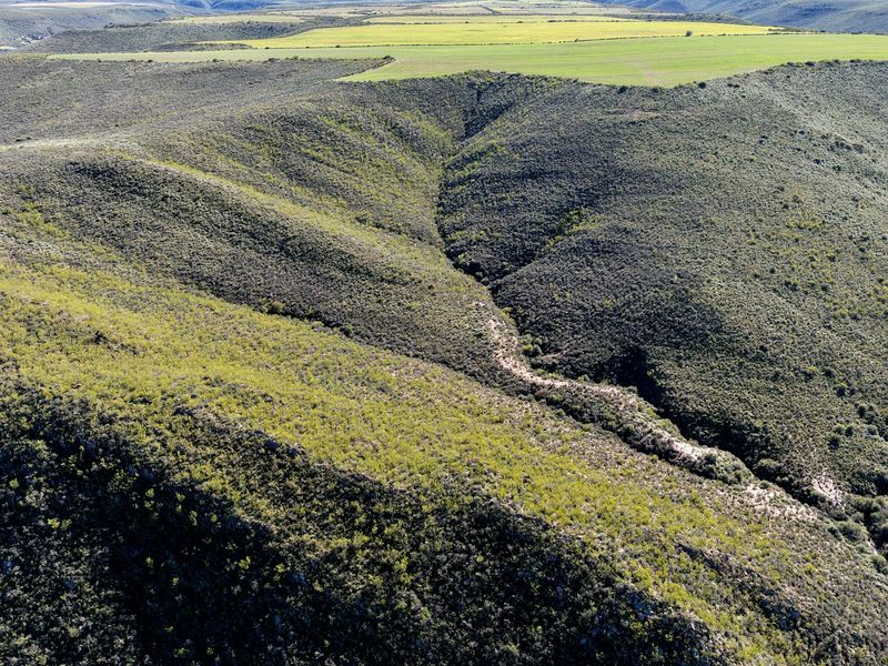 An aerial view of the expansive farm landscape, showcasing natural topography, rolling hills, and open fields.
