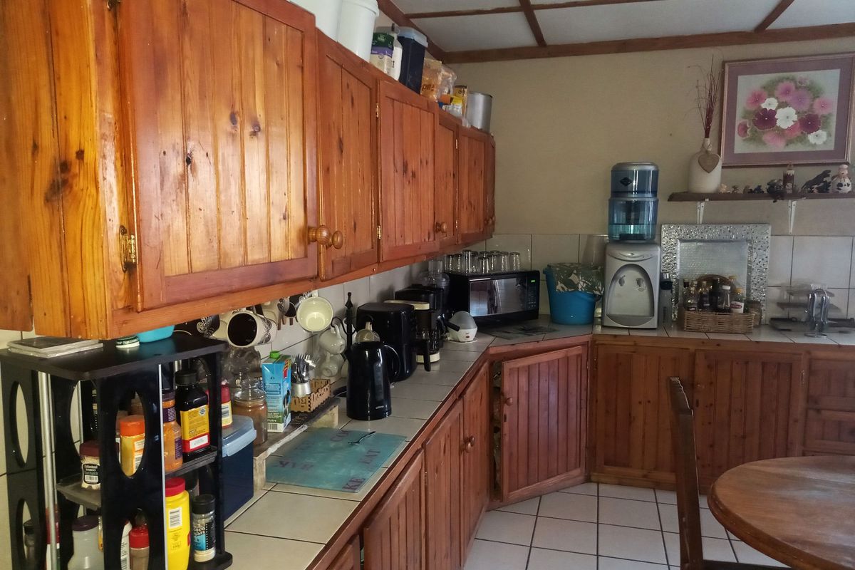 A rustic kitchen featuring traditional timber cabinetry, tiled countertops, and tiled flooring, offering a functional layout with ample storage space.