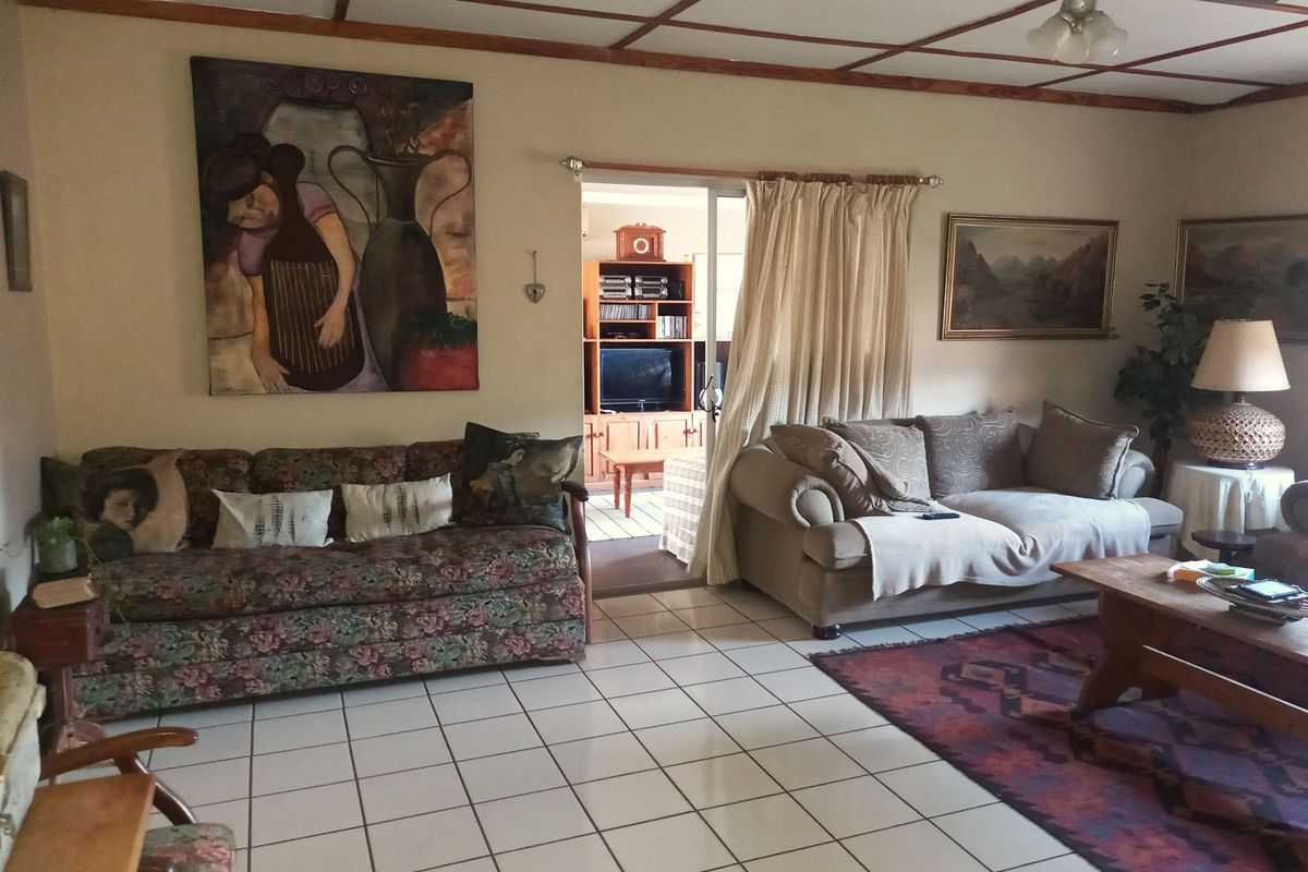 A spacious living room featuring tiled flooring, a ceiling fan, and a sliding door leading to an adjacent room.
