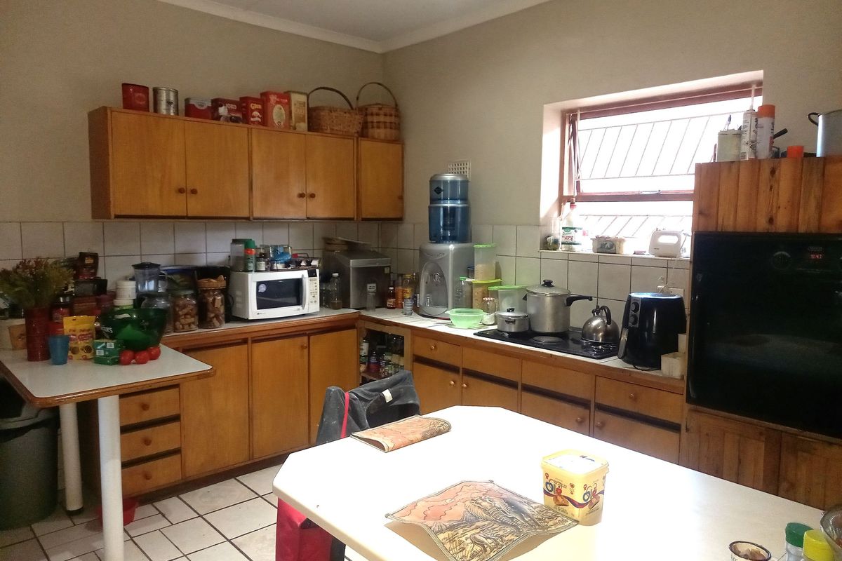 A functional kitchen featuring wooden cabinetry, tiled backsplash, and a built-in hob, offering a practical layout for daily meal preparation.