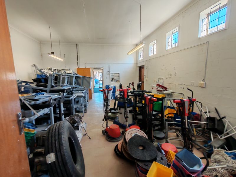 A functional industrial utility space featuring high-level windows, concrete flooring, and fluorescent lighting, currently utilized for storage.