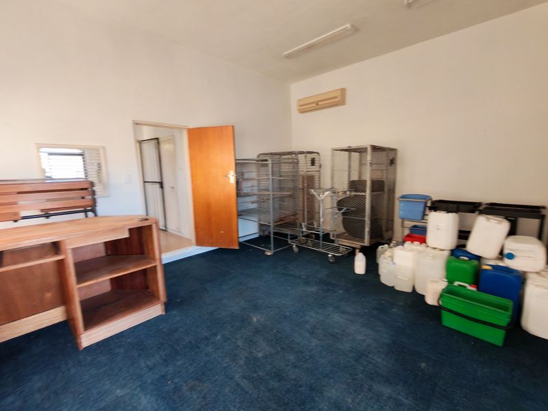Functional utility space featuring a split-system air conditioner, fluorescent lighting, and direct access to an adjacent room.