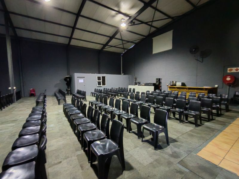 Spacious industrial open-plan area featuring high ceilings with exposed steel trusses, painted masonry walls, and durable tiled flooring, suitable for versatile commercial use.