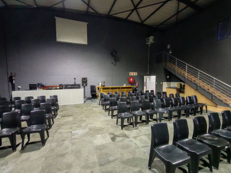 Spacious industrial open-plan area featuring high ceilings with exposed steel trusses, a mezzanine staircase, and a built-in service counter.
