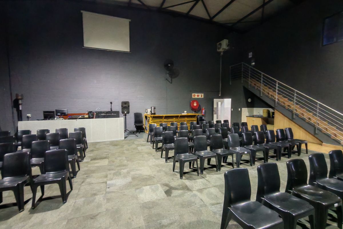 Spacious industrial open-plan area featuring high ceilings with exposed steel trusses, a mezzanine staircase, and a built-in service counter.