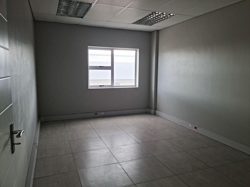 A clean, empty office space featuring tiled flooring, suspended ceiling with recessed lighting, and perimeter trunking for electrical connectivity.