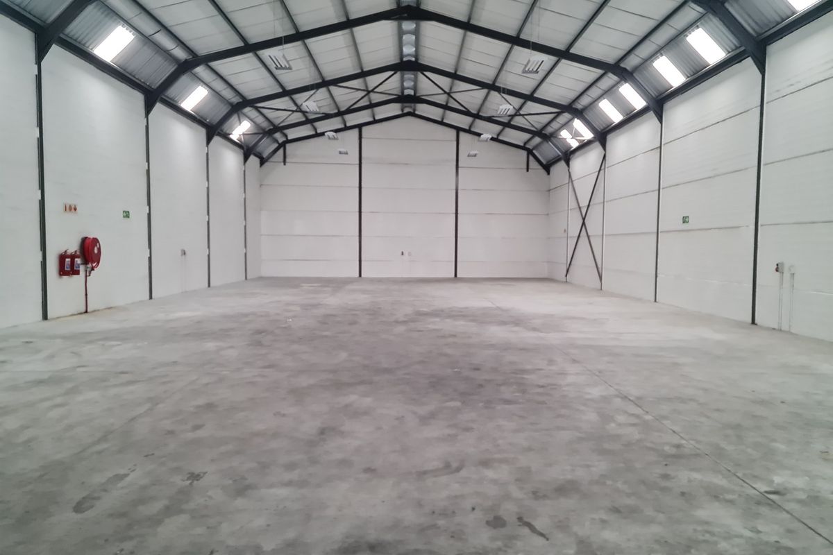 A spacious, clean industrial warehouse unit featuring a high-clearance steel portal frame, polished concrete flooring, and integrated skylights for natural illumination.