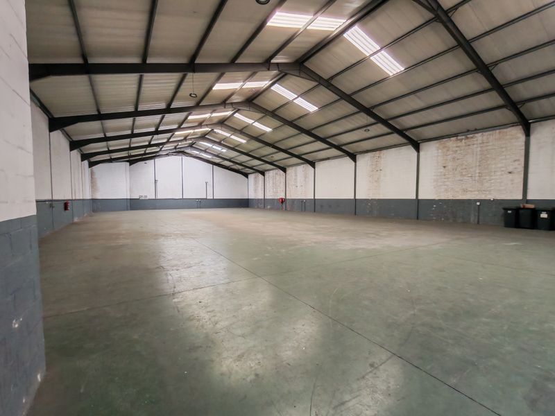 Spacious industrial warehouse unit featuring high ceilings with integrated skylights, durable concrete flooring, and a clear-span steel portal frame structure.