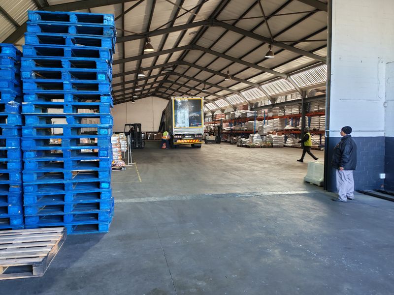 Spacious industrial warehouse facility featuring high-bay lighting, steel portal frame construction, and extensive racking systems for efficient storage and logistics operations.