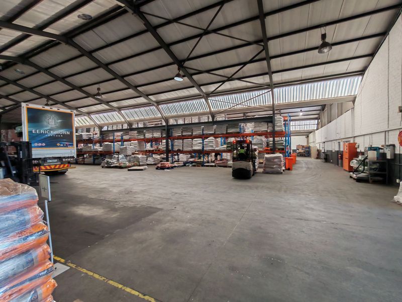 Spacious industrial warehouse featuring high-bay lighting, concrete flooring, and extensive steel racking systems suitable for logistics and storage operations.