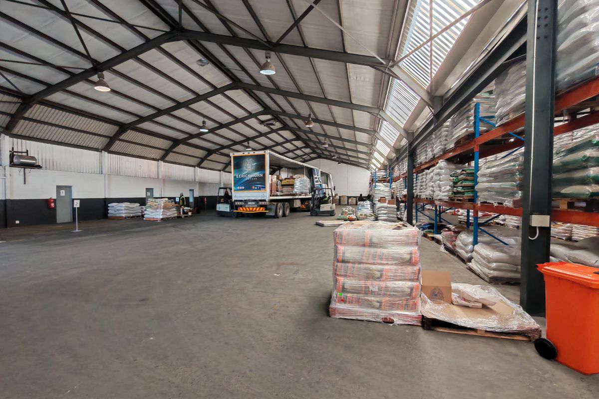 Spacious industrial warehouse featuring a steel portal frame structure, high-bay lighting, integrated skylights, and extensive heavy-duty pallet racking for efficient storage and logistics operations.