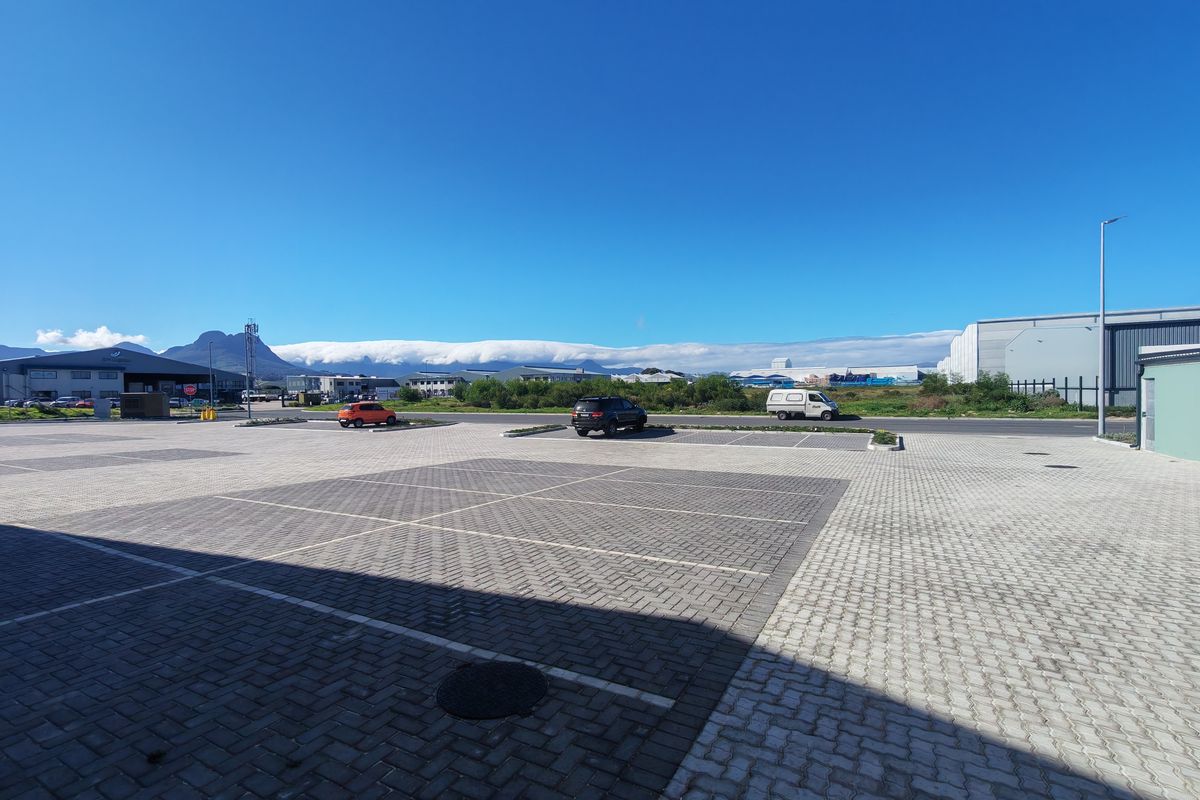 A wide-angle view of a paved industrial parking lot with marked bays and clear access, set against a mountain backdrop.