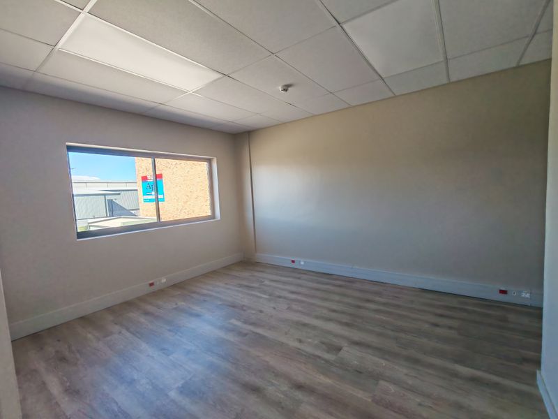A clean, vacant office space featuring modern laminate flooring, a suspended ceiling with recessed lighting, and perimeter electrical trunking for connectivity.