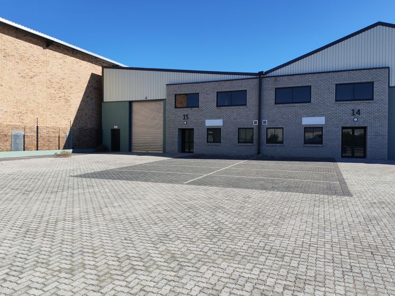 Exterior view of industrial units featuring brick facades, roller shutter doors, and a paved parking area.