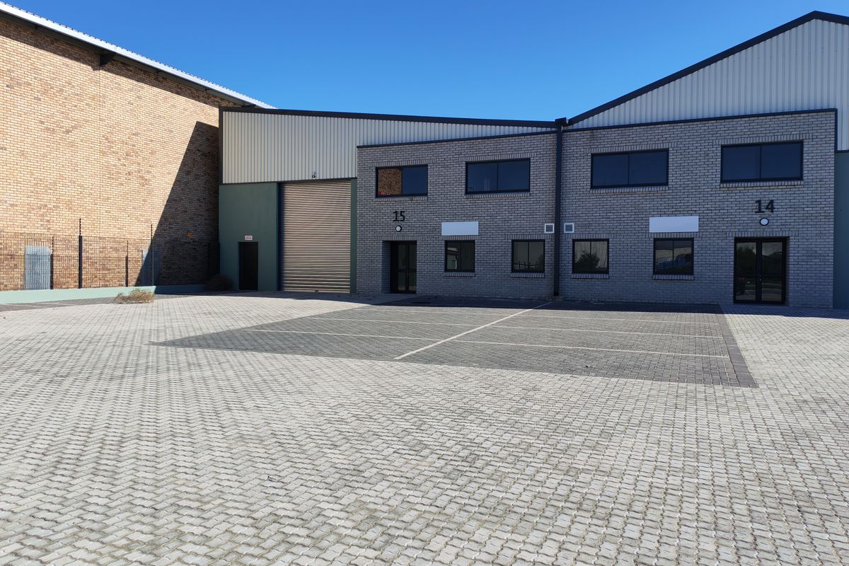 Exterior view of industrial units featuring brick facades, roller shutter doors, and a paved parking area.