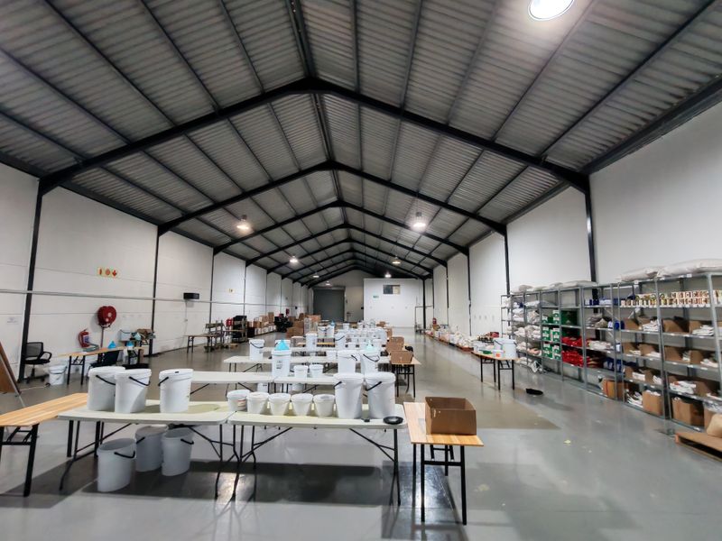 Spacious industrial warehouse featuring high ceilings with exposed steel trusses, durable epoxy flooring, and extensive built-in metal shelving for storage.