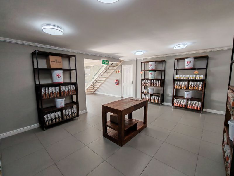 Open plan industrial space featuring tiled flooring, recessed lighting, and a staircase leading to an upper level, suitable for showroom or office use.