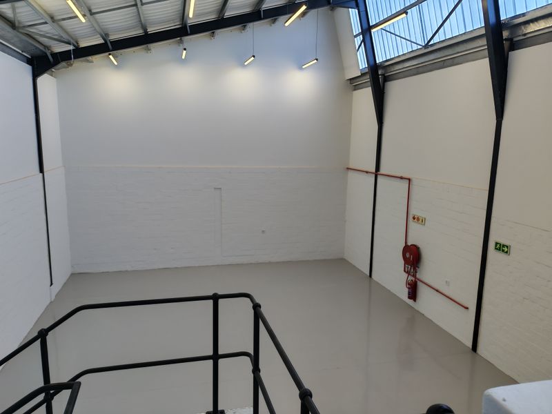 A clean, open-plan industrial utility space featuring high ceilings with exposed steel trusses, epoxy flooring, and integrated fire safety equipment.