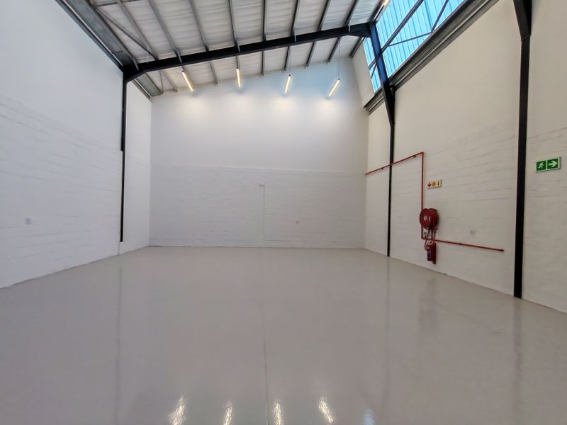 Spacious industrial warehouse unit featuring high ceilings, exposed steel structure, polished epoxy flooring, and integrated fire safety equipment.
