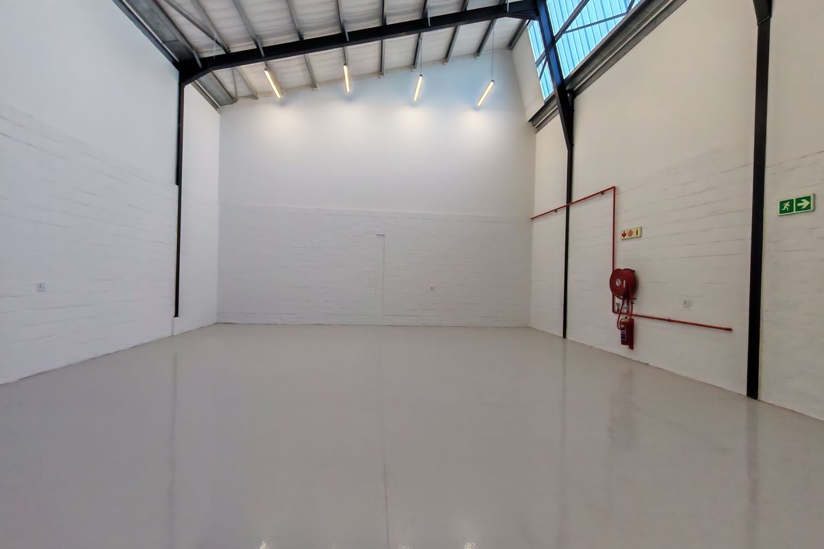 Spacious industrial warehouse unit featuring high ceilings, exposed steel structure, polished epoxy flooring, and integrated fire safety equipment.