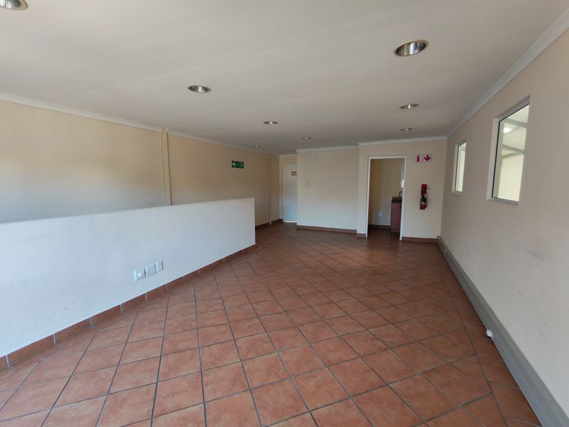 An open-plan office space featuring tiled flooring, recessed downlighting, and neutral wall finishes, suitable for a variety of commercial or industrial business operations.