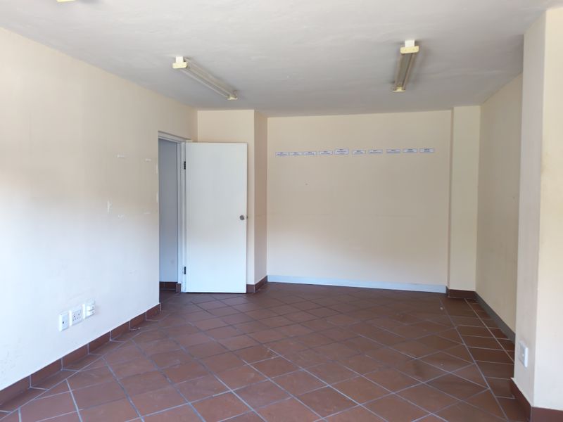 A vacant, functional office space featuring neutral walls, tiled flooring, and overhead fluorescent lighting, suitable for various commercial or administrative uses.