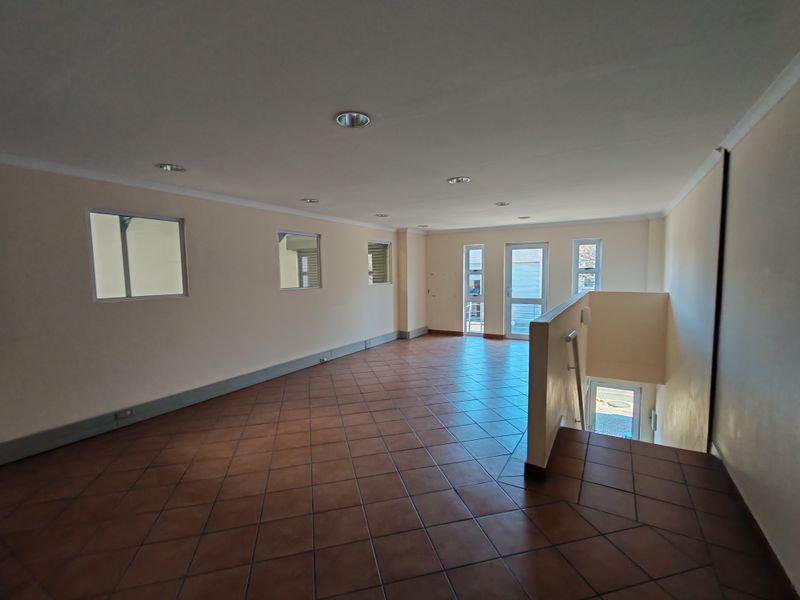 Spacious open-plan industrial office or utility area featuring ceramic tile flooring, recessed lighting, and a staircase with a metal handrail.