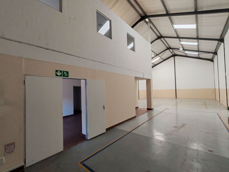 Spacious industrial warehouse unit featuring high ceilings with exposed steel trusses, skylights for natural light, and durable concrete flooring.